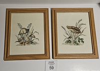 Front view of the two framed mushroom-themed needlepoint artworks side by side against a white background
