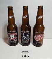 Front view of three brown collectible beer bottles featuring Montreal Canadiens, Toronto Maple Leafs, and Detroit Red Wings logos.