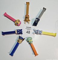 Top view of seven PEZ dispensers arranged in a circle showing character heads and stems.