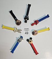 Top view of seven PEZ dispensers laid out in circle showing character heads: Darth Vader, Taz, Bugs Bunny, Mickey Mouse, Spider-Man, and two others.