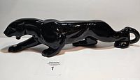 Side view of glossy black ceramic panther figurine, showing crouching pose and muscular details.