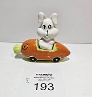 Front view of the assembled salt and pepper set showing white bunny sitting in carrot car with painted wheels and green carrot top.