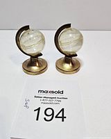 Pair of vintage salt and pepper shakers shaped as clear plastic globes on brass-colored metal stands.