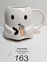 Front view of the white ceramic ghost shaped Tim Hortons mug with black eyes, holding a donut and a Tim Hortons cup illustration.