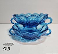 Two vintage Anchor Hocking blue glass candy dishes stacked, showing scalloped edges and handles, deep blue color.