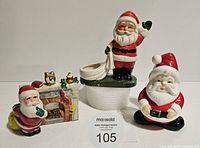 Three vintage ceramic Santa Claus Christmas decorations arranged on white surface, showing front and side details.