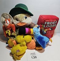 Full lot of six vintage plush toys including duck, Woodstock, Froot Loops box, Yosemite Sam, yellow bird, blue duck and caterpillar, arranged on white background.