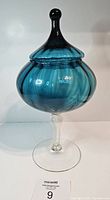 Front view of vintage turquoise Empoli glass jar with lid on clear stemmed base.