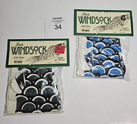 Two fish design windsocks in packaging, one with black scales and one with blue scales under header cards stating 100% cotton and Pier One Imports.