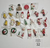 Photo showing various wooden Christmas ornaments packaged individually in plastic bags, including elves, snowmen, bells, wreaths, and other holiday figures.