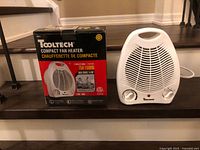 Heater front view beside original box showing branding and wattage info