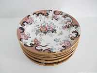 Stack of ten Ashworth Bros floral gilt rim dinner plates viewed from top