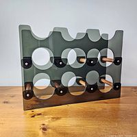 Front view of smoked lucite wine rack showing nine circular slots and wood dowels
