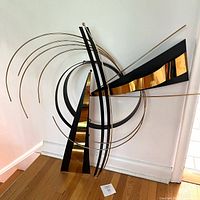 Full view of brass and black wall sculpture leaning on wall