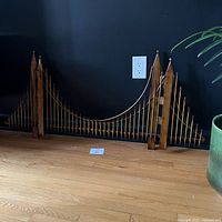 Full view of metal suspension bridge sculpture showing overall design and scale