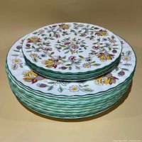 Stack of dinner and salad plates showing pattern and green rim