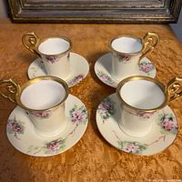 Top view of four cup and saucer sets showing floral design and gilt handles