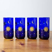 Front view of four cobalt blue tumblers with celestial design
