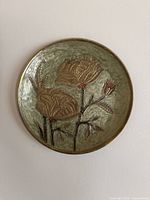 Full view of decorative brass wall plate with green enamel and embossed floral motif