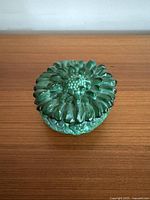 Top view of green glass trinket box lid showing large flower detail