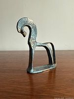 Side view of the miniature bronze horse statue showing arched neck and engraved details.