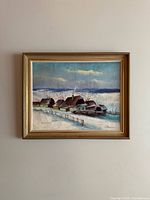 Full view of the framed signed winter landscape painting showing quaint houses, snow, fence, and cloudy sky.