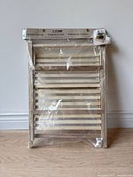 Front view of the small wooden shelf in packaging showing the full shelf and label.