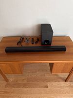 Full view of Sony SA-CT80 soundbar, subwoofer, remote control, and cables on wooden table against wall