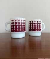 Front view of two vintage white mugs with red square and white polka dot pattern