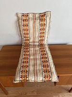 Full view of the long rectangular cushion or seat pad, showing the floral pattern and woven fabric.