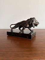 Side view of the lion sculpture showing full figure and base on a wooden surface against white background.
