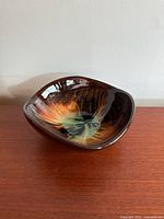 Photo showing the interior and side of the pottery bowl with orange feather pattern.