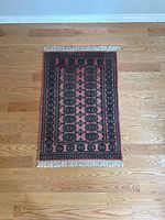 Full top view of vintage oriental style rug on wooden floor showing overall pattern and colors.
