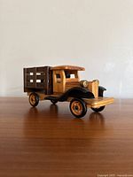 Front and side angled view of the wooden toy truck showing detailed wood craftsmanship and paint accents.