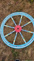 Blue striped folk art wagon wheel lying on grass