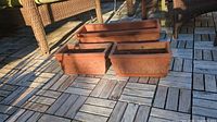 Three rectangular terracotta planters grouped on deck