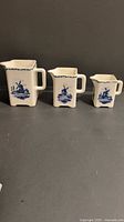 three graduated Delft Blue creamers side by side