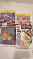 Front view of four costume pattern envelopes including Sailor Moon, historical gowns, princess dresses and insect/flower outfits