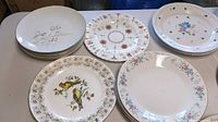 Stacks of assorted patterned plates showing bird motif, gold scroll, floral rims