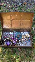 Open metal box showing assorted costume jewelry