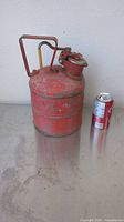 Full view of red gas can beside soda can for scale