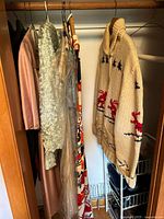 Clothing rack with multiple vintage clothing items including wool sweater and dresses