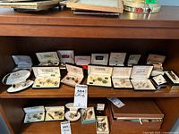 Full overview of shelf with multiple original jewelry boxes containing cufflinks and tie bars