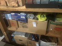 Shelves containing boxes of electrical and plumbing supplies, including Samsung VR540C component box, cardboard boxes, and plastic bags with parts.