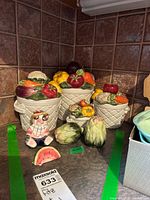 Photo of the full set showing four Fitz and Floyd ceramic basket canisters with colorful vegetable tops, three ceramic salt and pepper shakers, and a small watermelon slice figure.