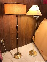 Pair of floor lamps together. One torchiere style with drum shade; one with adjustable arm and tapered shade.