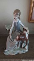 Front view of the Lladro porcelain figurine showing the seated girl holding the fawn, slight damage visible on ear.