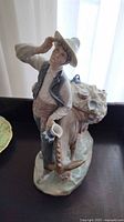 Front view of the Lladro porcelain figurine showing the peddler holding his hat and the detailed donkey with pottery and goods.