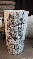 Front view of white porcelain vase with black abstract architectural drawings showing domes and spires.