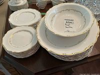 Stacks of dinner and dessert plates alongside serving bowl under another bowl